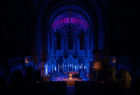 Blick auf eine dunkel beleuchtete Kirche mit bunten Lichtakzenten.